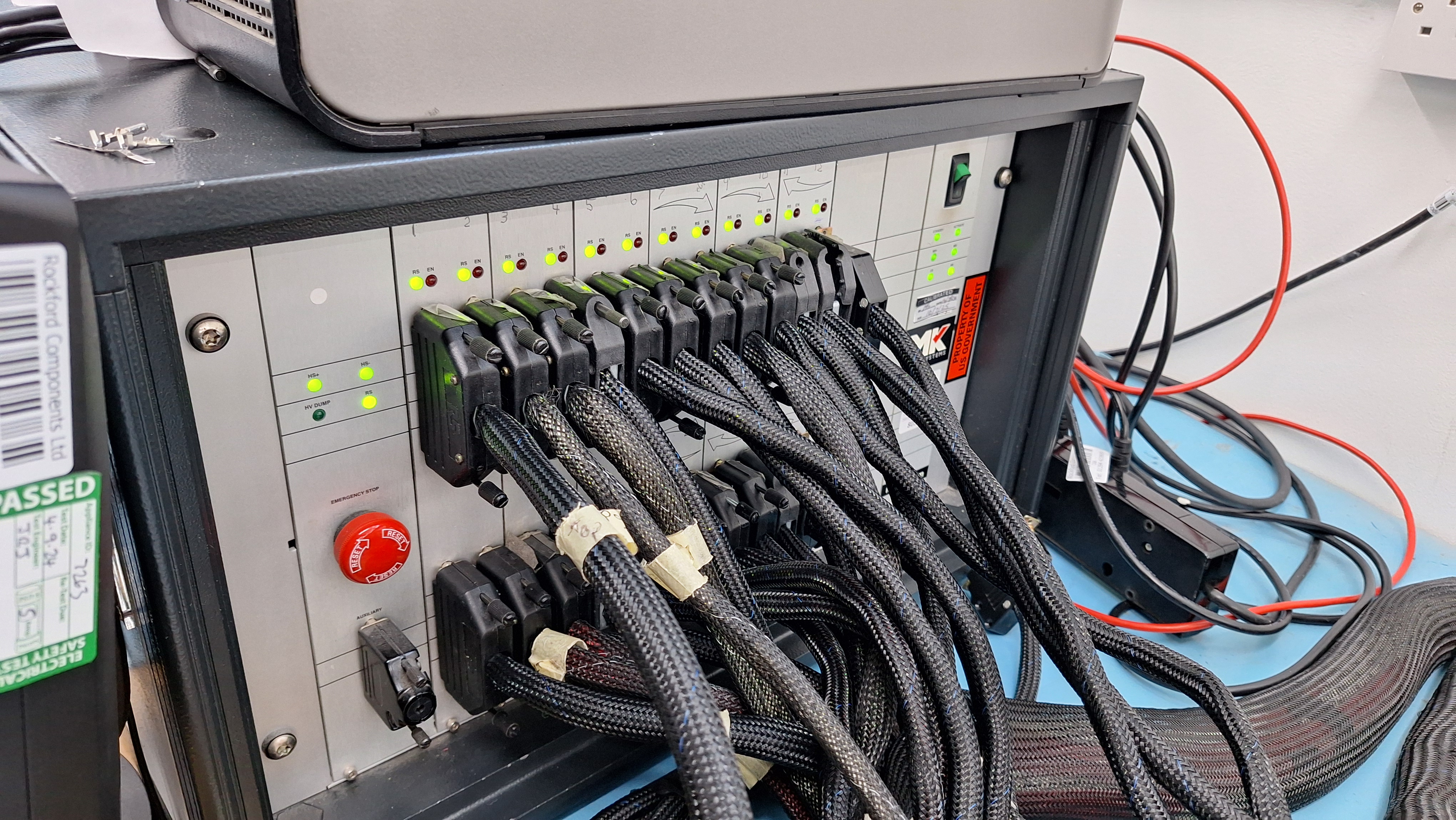 Rack-mounted test equipment with status indicators and dense cable looms, used for functional testing of completed assemblies